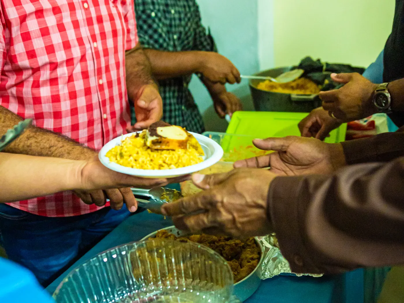 Manos que pasan un plato de arroz recién servido en el comedor